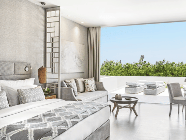 Luxurious junior suite at Ikos Aria with a private garden and garden view, featuring a spacious bedroom, elegant decor, and outdoor seating area.