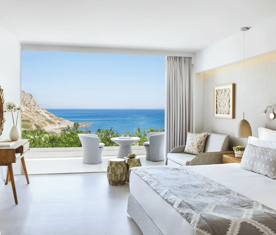 Ikos Aria Superior Room with modern furnishings, a king-sized bed, a private terrace, and a panoramic sea view.