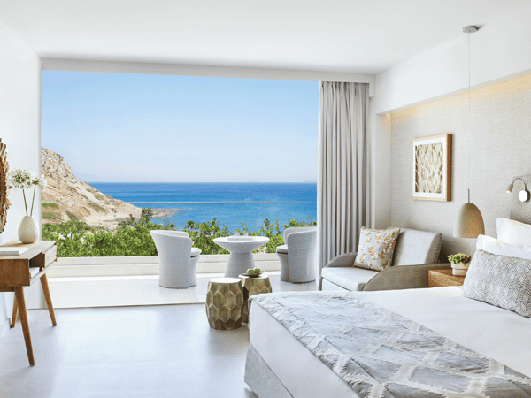 Ikos Aria Superior Room with modern furnishings, a king-sized bed, a private terrace, and a panoramic sea view.