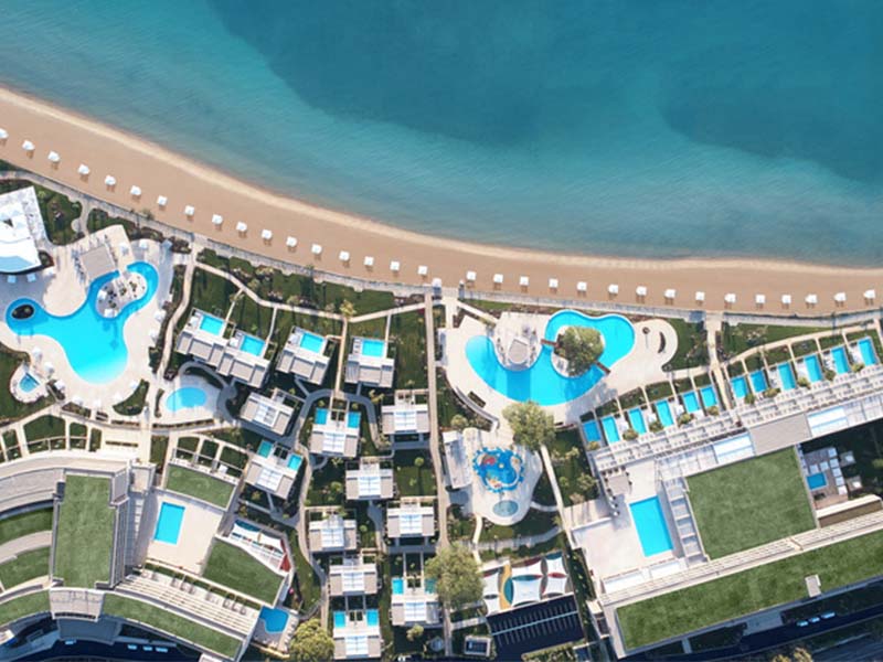 Aerial view of Ikos Dassia resort, showcasing swimming pools, gardens, and Dassia Beach on the Ionian Sea.
