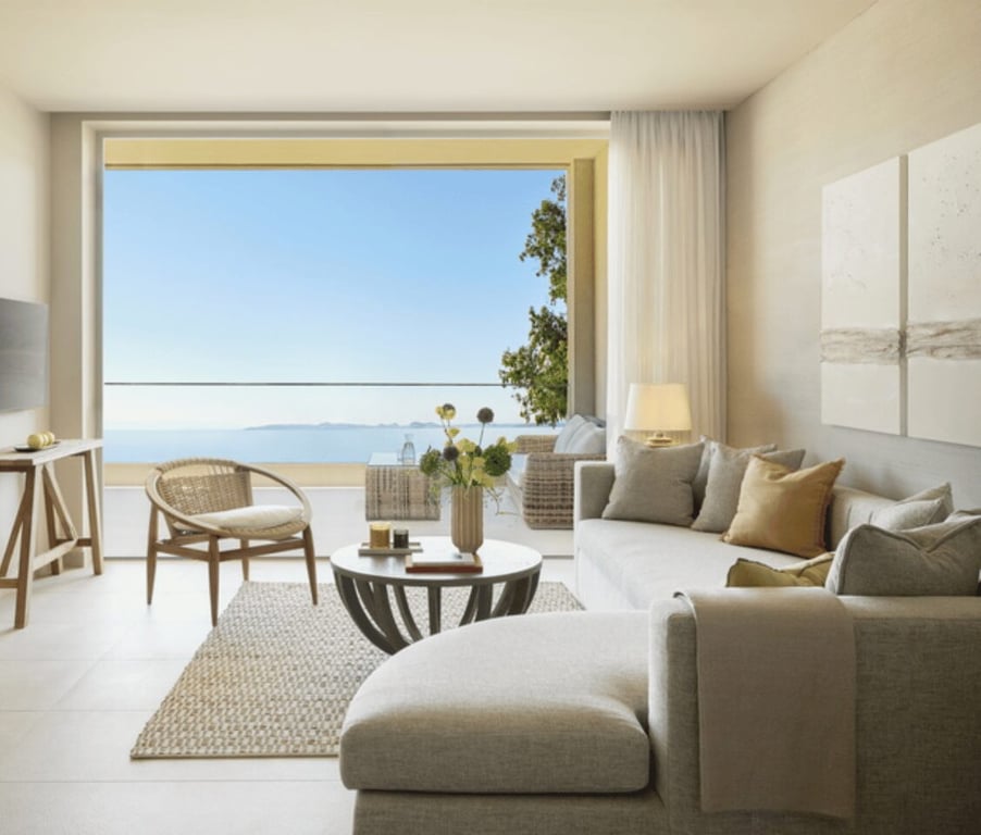 Ikos Odisia Deluxe One Bedroom Bungalow Suite with sea front view, featuring elegant interior design with sofa and armchair.