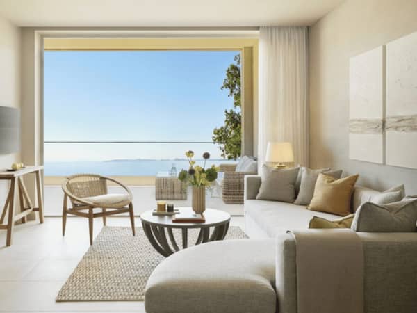 Ikos Odisia Deluxe One Bedroom Bungalow Suite with sea front view, featuring elegant interior design with sofa and armchair.