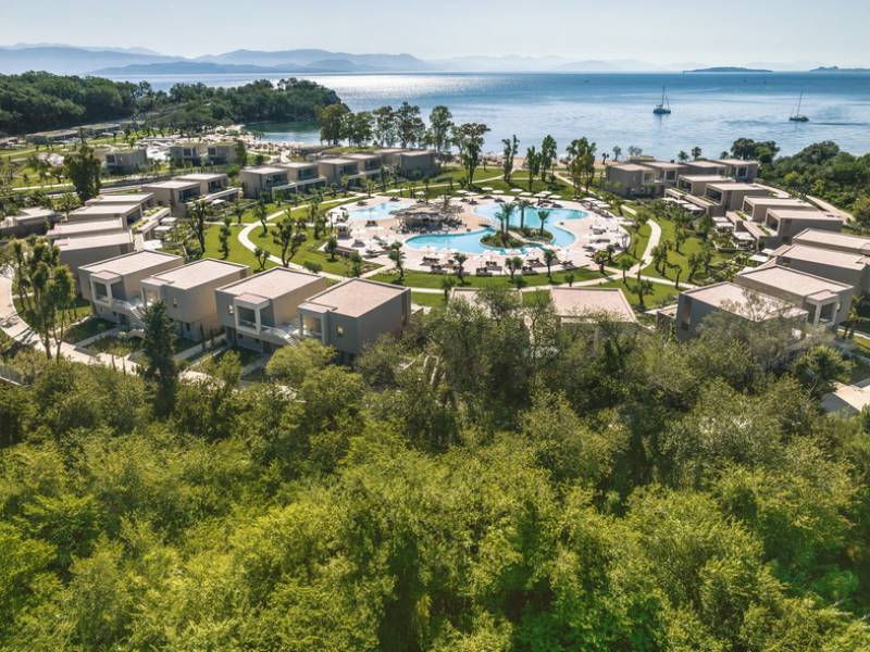 Aerial view of Ikos Odisia resort featuring a circular layout with central pool, lush greenery, and coastal surroundings.