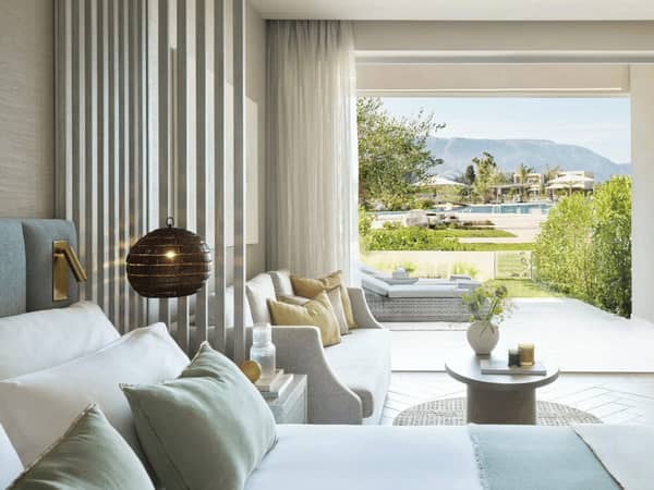 Ikos Odisia Junior Bungalow Suite interior with open-plan design, featuring access to a private garden and pool view.