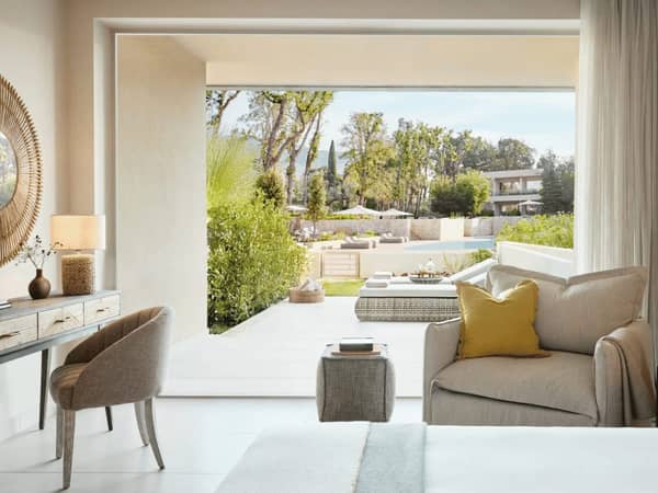 Ikos Odisia hotel room with modern decor, large opening to private garden and pool view.