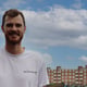 Smiling Jamie Murray wearing an 'Active Away' t-shirt with historic buildings and a blue sky in the background.