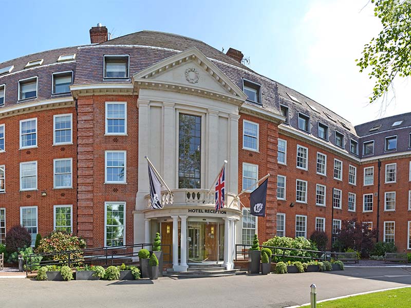 The Lensbury hotel entrance with flags and greenery, known for hosting Junior Tennis Camps.