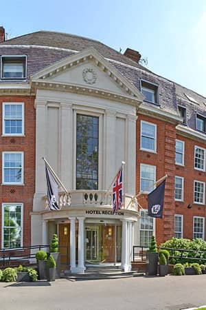 The Lensbury hotel entrance with flags and greenery, known for hosting Junior Tennis Camps.