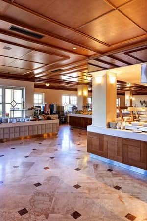 Kalimera Kriti Gallery buffet area with wooden décor, large windows, and various serving stations, filled with natural light.