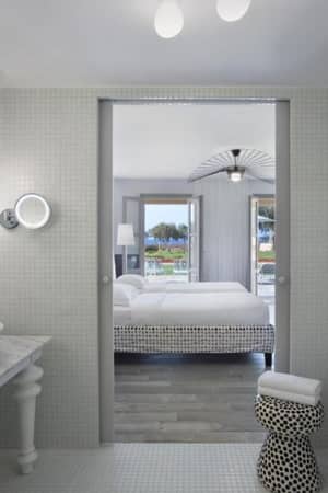 Hotel room at Kalimera Kriti, showing a bathroom with double sinks and a bathtub, and a bedroom visible through a door with sea views.