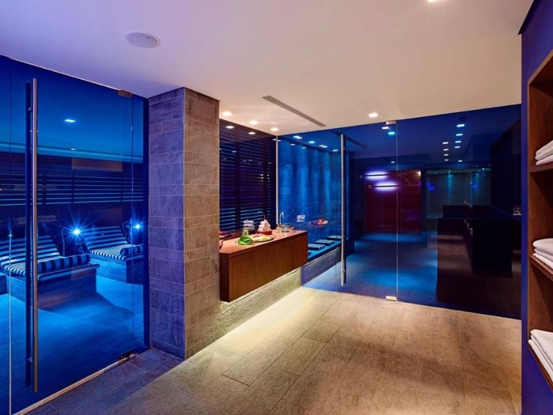 Interior of the Kalimera Kriti Hotel's spa bar, featuring modern decor, ambient lighting, and a wooden reception desk with towels.