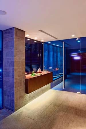 Interior of the Kalimera Kriti Hotel's spa bar, featuring modern decor, ambient lighting, and a wooden reception desk with towels.