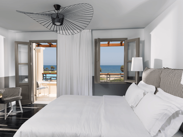 Deluxe sea view room at Kalimera Kriti Hotel with modern decor, double bed, and balcony overlooking the sea and pool.