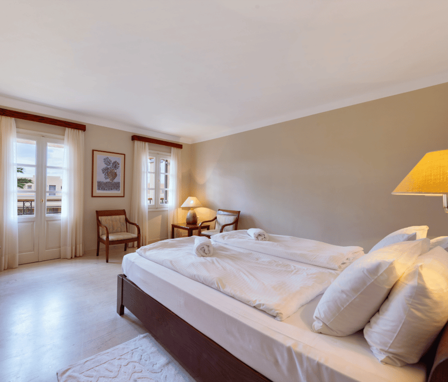 Hotel room at Kalimera Kriti with double bed, wooden furniture, and large windows offering a mountain view.