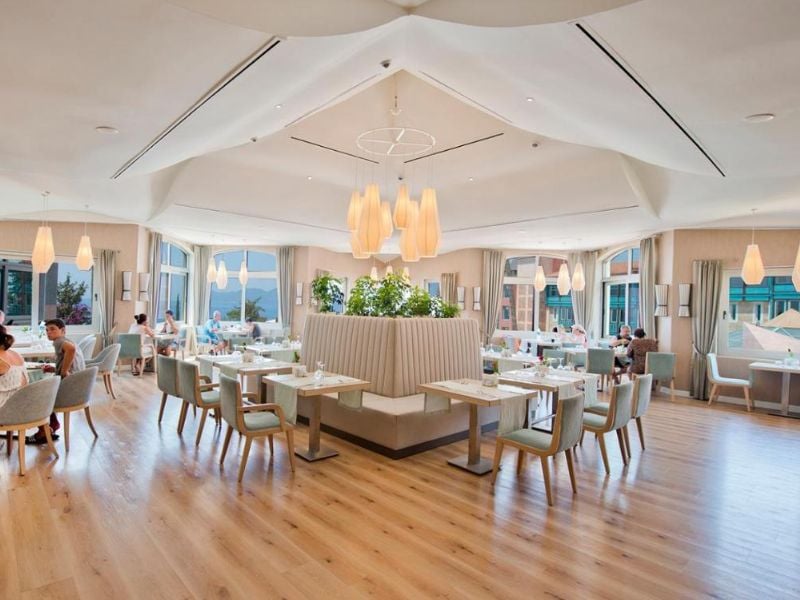 Spacious interior of Liberty Lykia's Center Restaurant with modern white decor, pendant lights, and large windows.