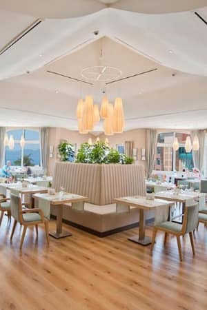 Spacious interior of Liberty Lykia's Center Restaurant with modern white decor, pendant lights, and large windows.