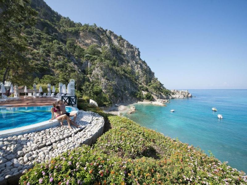 View from Liberty Lykia pool overlooking turquoise Mediterranean Sea and lush cliffs.