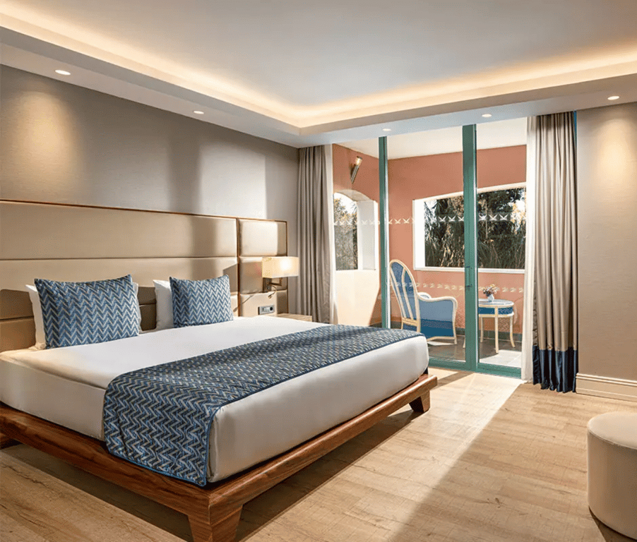 Liberty Sentido Deluxe Suite with king-size bed, elegant decor, blue and white bedding, and a balcony with seating.