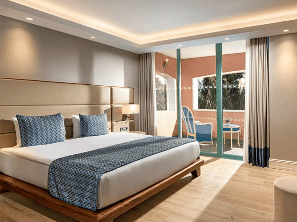 Liberty Sentido Deluxe Suite with king-size bed, elegant decor, blue and white bedding, and a balcony with seating.
