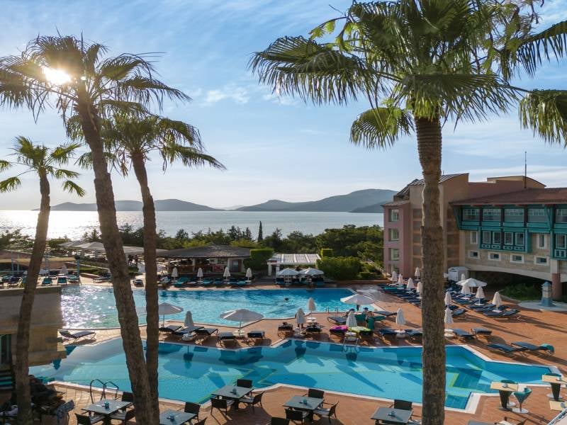 Outdoor pool area at Liberty Sentido Hotel with sun loungers, palm trees, and a sea view in the background.