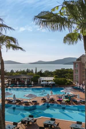 Outdoor pool area at Liberty Sentido Hotel with sun loungers, palm trees, and a sea view in the background.