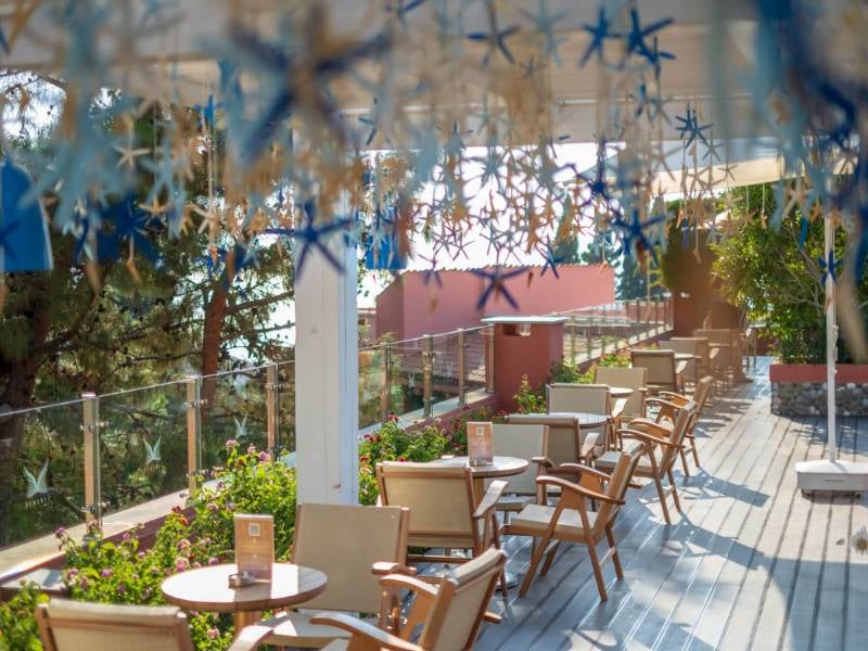 Outdoor terrace at Liberty Sentido Gallery Restaurant with wooden chairs, green plants, and star decorations.