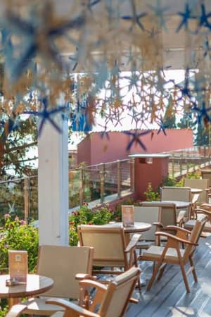 Outdoor terrace at Liberty Sentido Gallery Restaurant with wooden chairs, green plants, and star decorations.