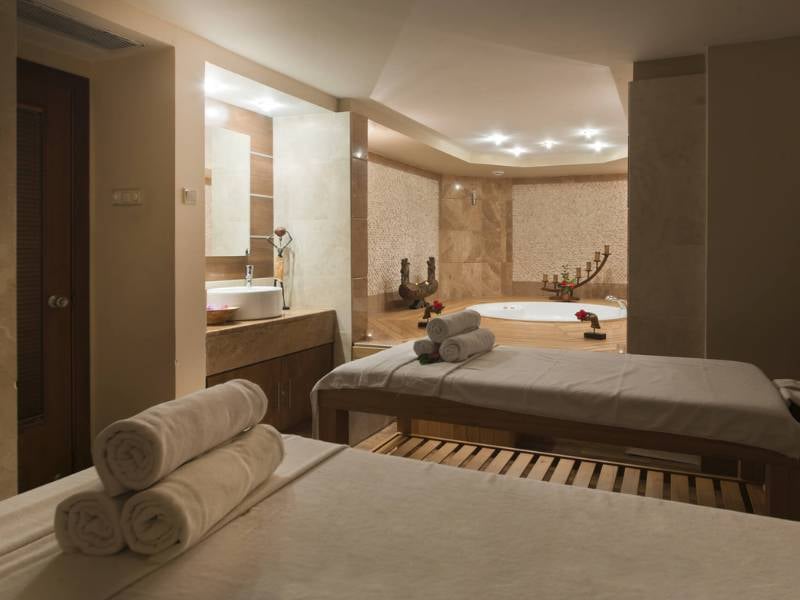 Serene spa room at Liberty Sentido Gallery with massage tables, fresh towels, and a jacuzzi surrounded by rose petals.