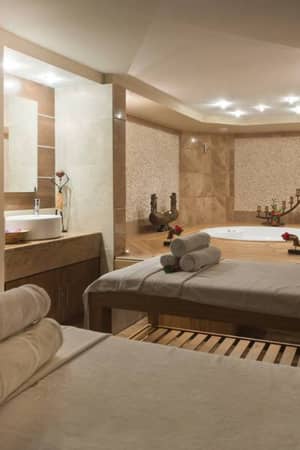 Serene spa room at Liberty Sentido Gallery with massage tables, fresh towels, and a jacuzzi surrounded by rose petals.