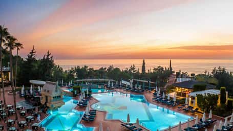 Aerial view of Liberty Sentido Lykia hotel with swimming pool and sunset over the sea.