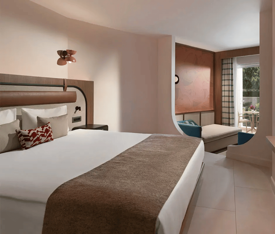 Deluxe room at Liberty Village with a large bed, elegant decor, and a seating area overlooking greenery.