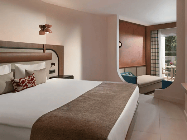 Deluxe room at Liberty Village with a large bed, elegant decor, and a seating area overlooking greenery.