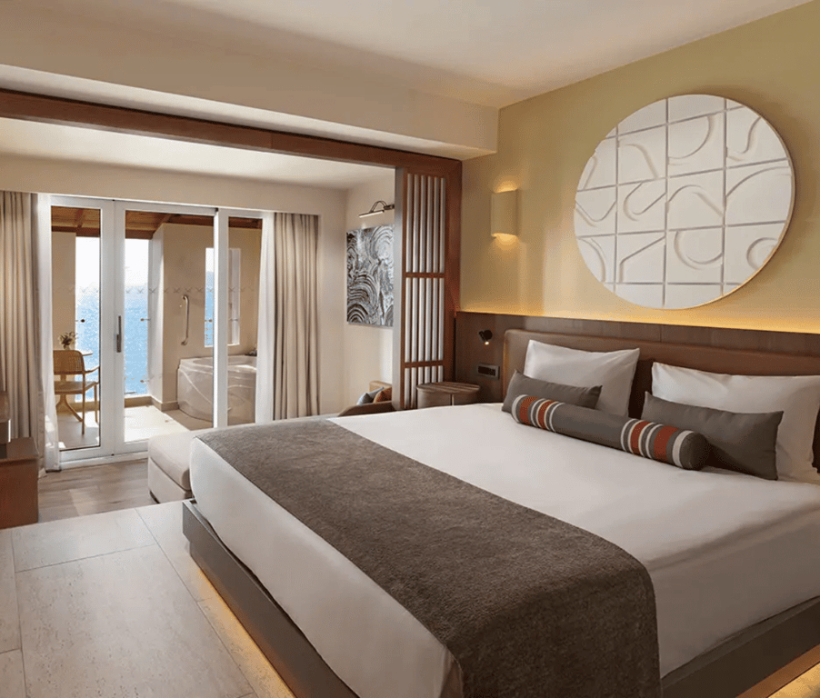 Luxurious hotel room at Liberty Village with a king-sized bed, balcony with sea view, and private jacuzzi.
