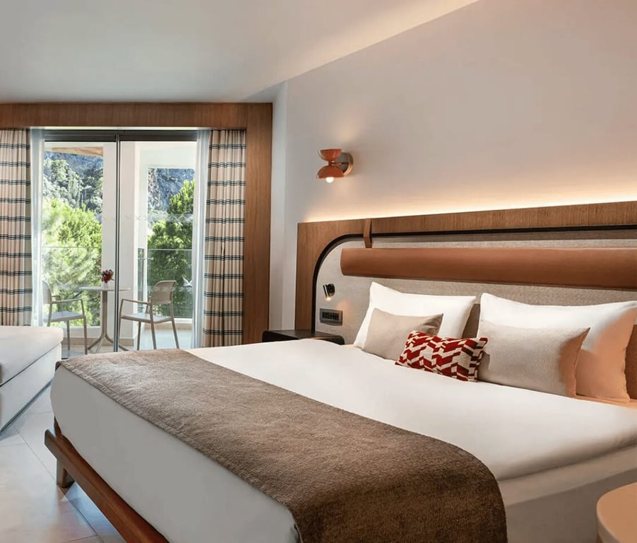 Deluxe connected room at Liberty Village with a large bed, elegant decor, and a balcony with a land view.