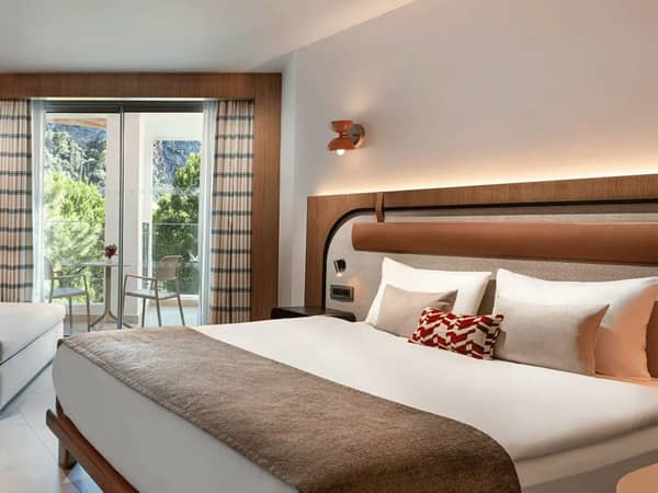 Deluxe connected room at Liberty Village with a large bed, elegant decor, and a balcony with a land view.