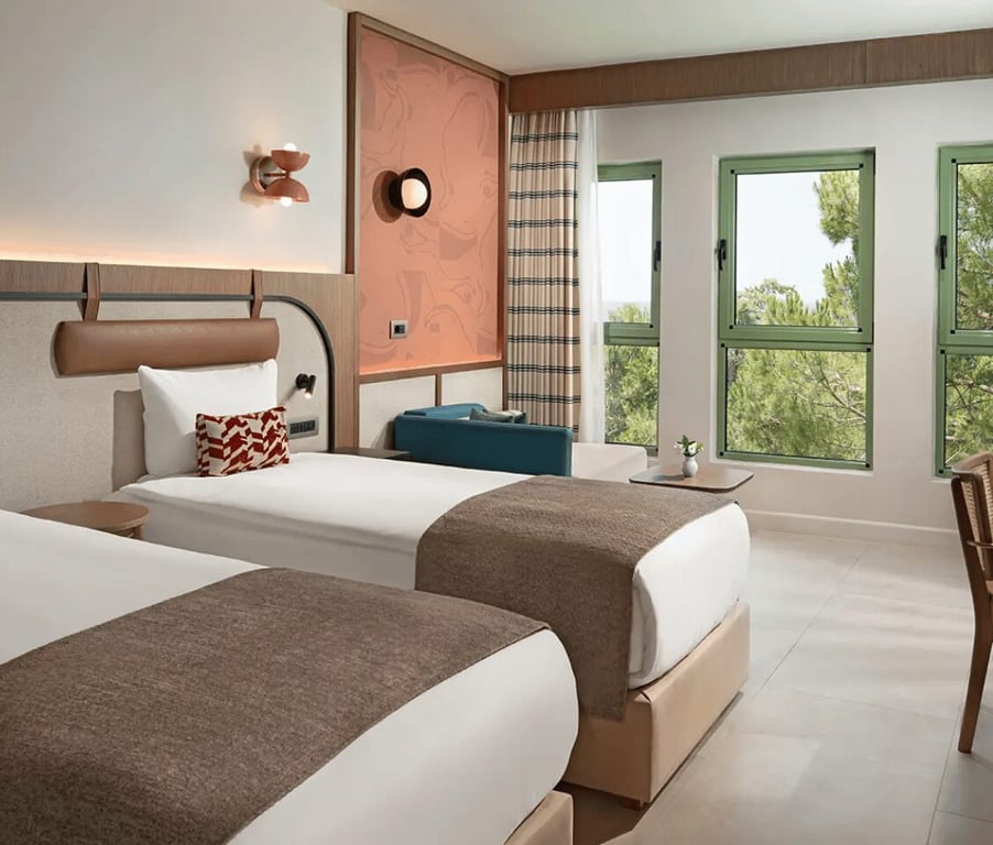 Luxurious family room in Liberty Village FTH with twin beds, modern decor, and large windows overlooking trees.