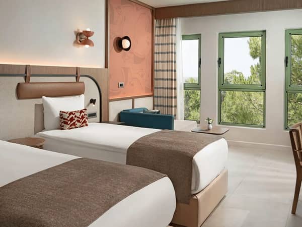 Luxurious family room in Liberty Village FTH with twin beds, modern decor, and large windows overlooking trees.