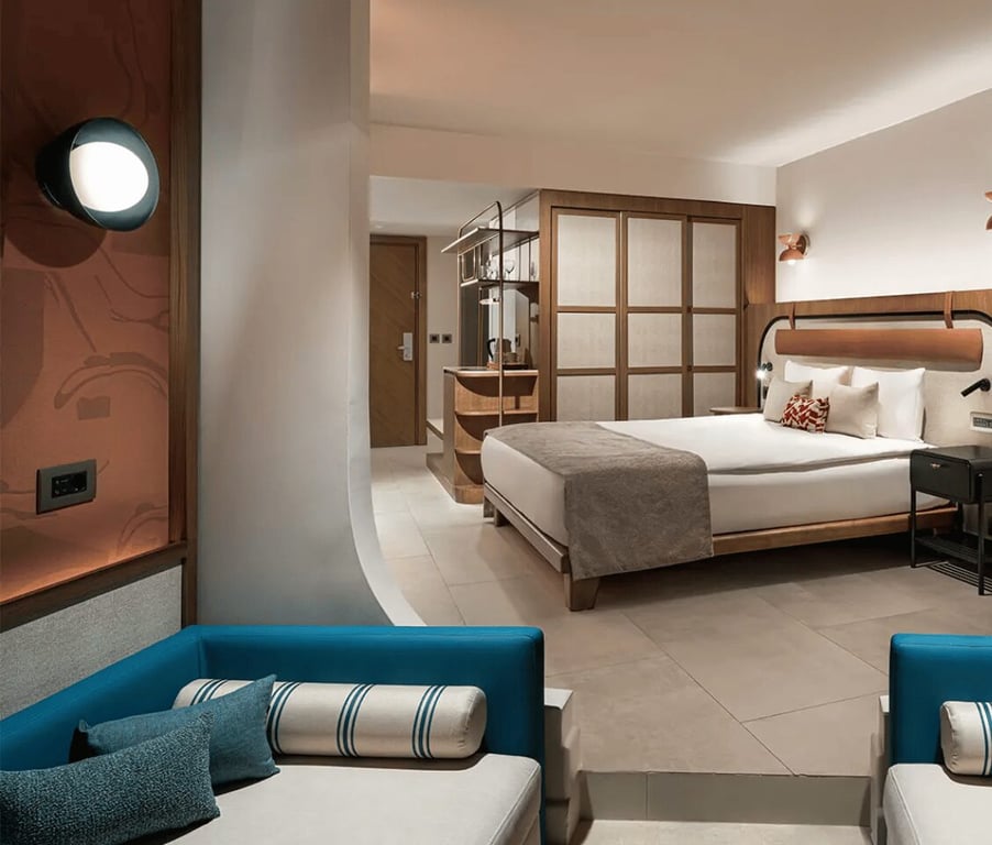 Modern, spacious hotel room with a large bed, stylish wooden partition, and cosy furnishings.