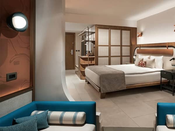 Modern, spacious hotel room with a large bed, stylish wooden partition, and cosy furnishings.