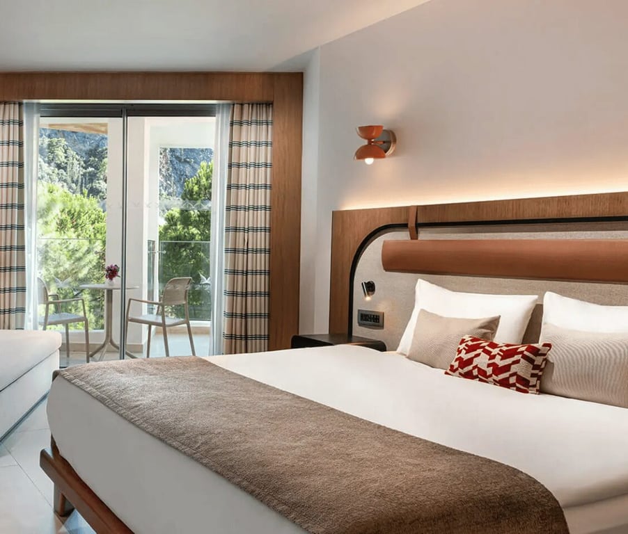 Liberty Village deluxe standard room with a double bed, modern decor, and a balcony offering a side sea view.