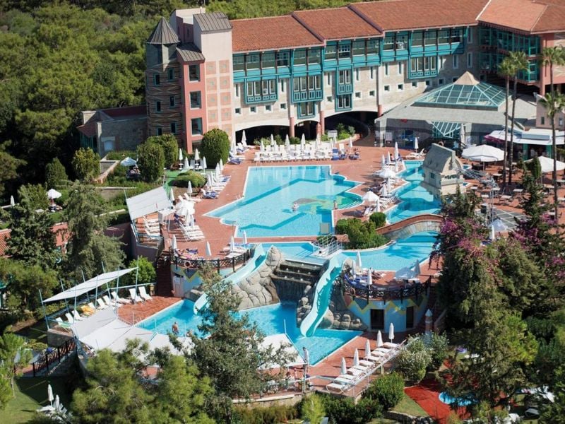 Aerial view of a luxury resort with a uniquely shaped outdoor pool, surrounded by lounge chairs and lush greenery.