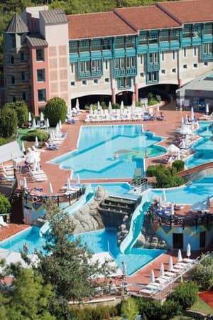 Aerial view of a luxury resort with a uniquely shaped outdoor pool, surrounded by lounge chairs and lush greenery.