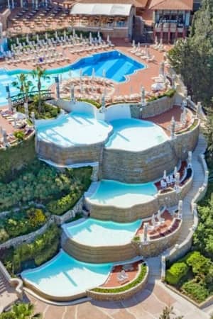 Aerial view of tiered infinity pools at Liberty Village, surrounded by greenery and leisure facilities.