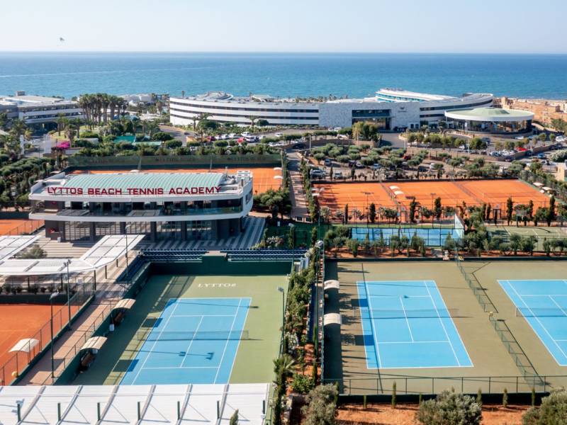 Aerial view of Lyttos Beach Tennis Academy with clay and hard courts near the Mediterranean Sea.