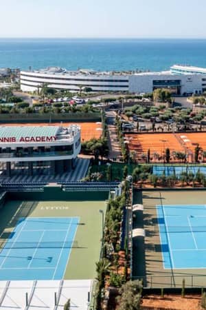 Aerial view of Lyttos Beach Tennis Academy with clay and hard courts near the Mediterranean Sea.