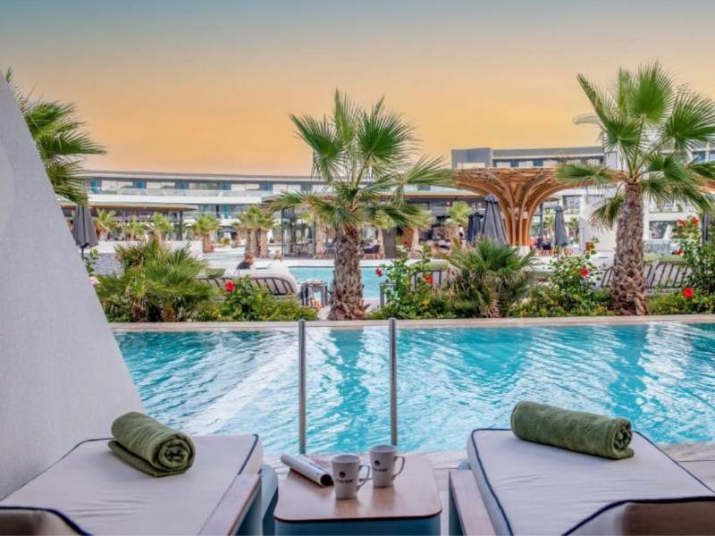 Lyttos Gallery private pool view with sun loungers, palm trees, and a modern architectural backdrop.