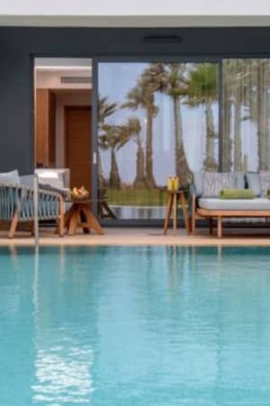 Private pool area at Lyttos Gallery with outdoor seating, featuring palm trees and garden view through large glass doors.