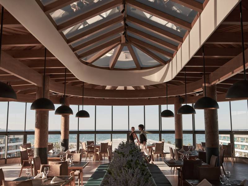 Interior of Lyttos Gallery Restaurant with wooden beams, pendant lights, and sea-view windows.
