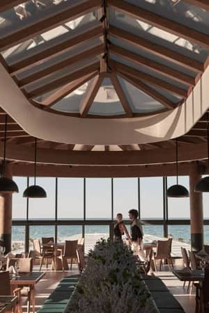 Interior of Lyttos Gallery Restaurant with wooden beams, pendant lights, and sea-view windows.