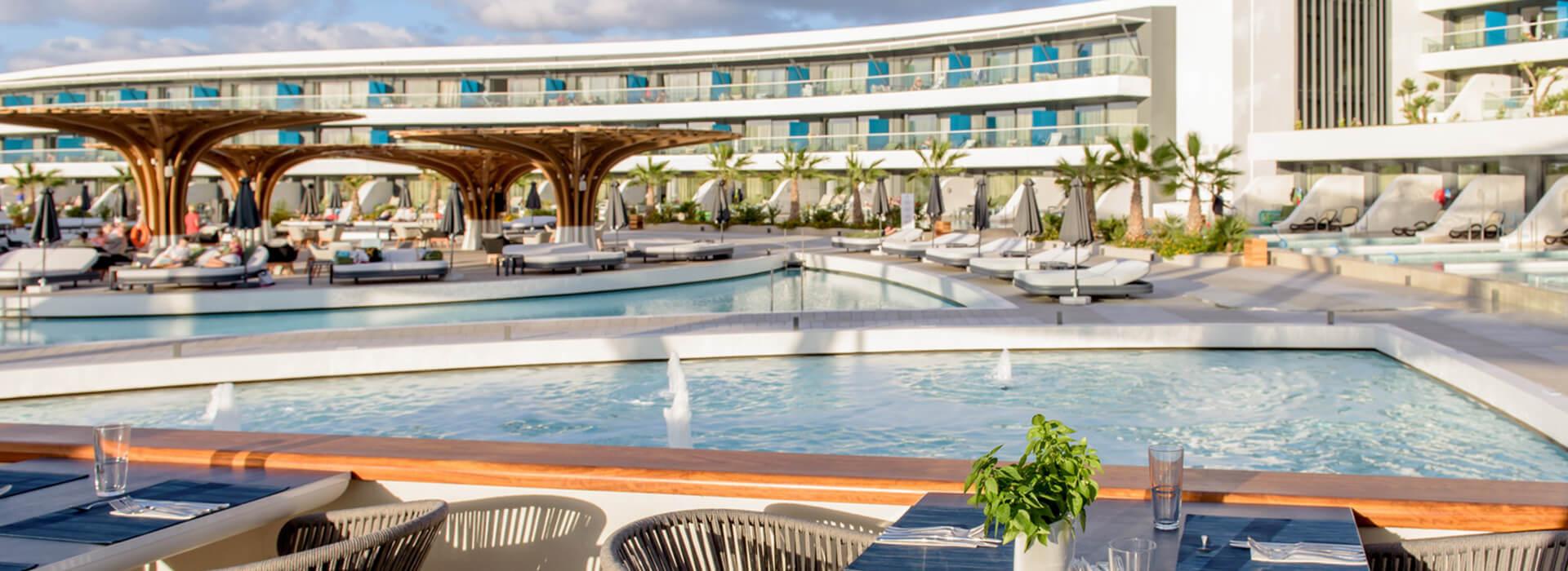 View of Lyttos Mare's swimming pools with modern architecture and lush surroundings.